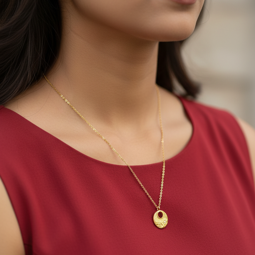 Gold circular necklace pendant on a model wearing red top