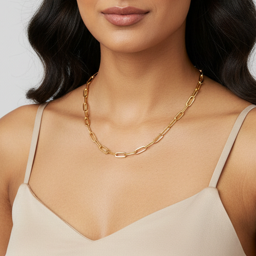 Woman wearing a gold chain necklace with a plain background