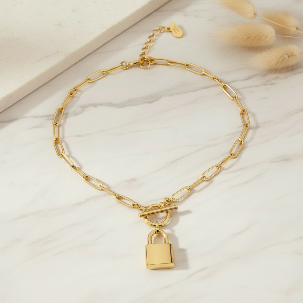 Gold necklace with a padlock pendant on a marble background