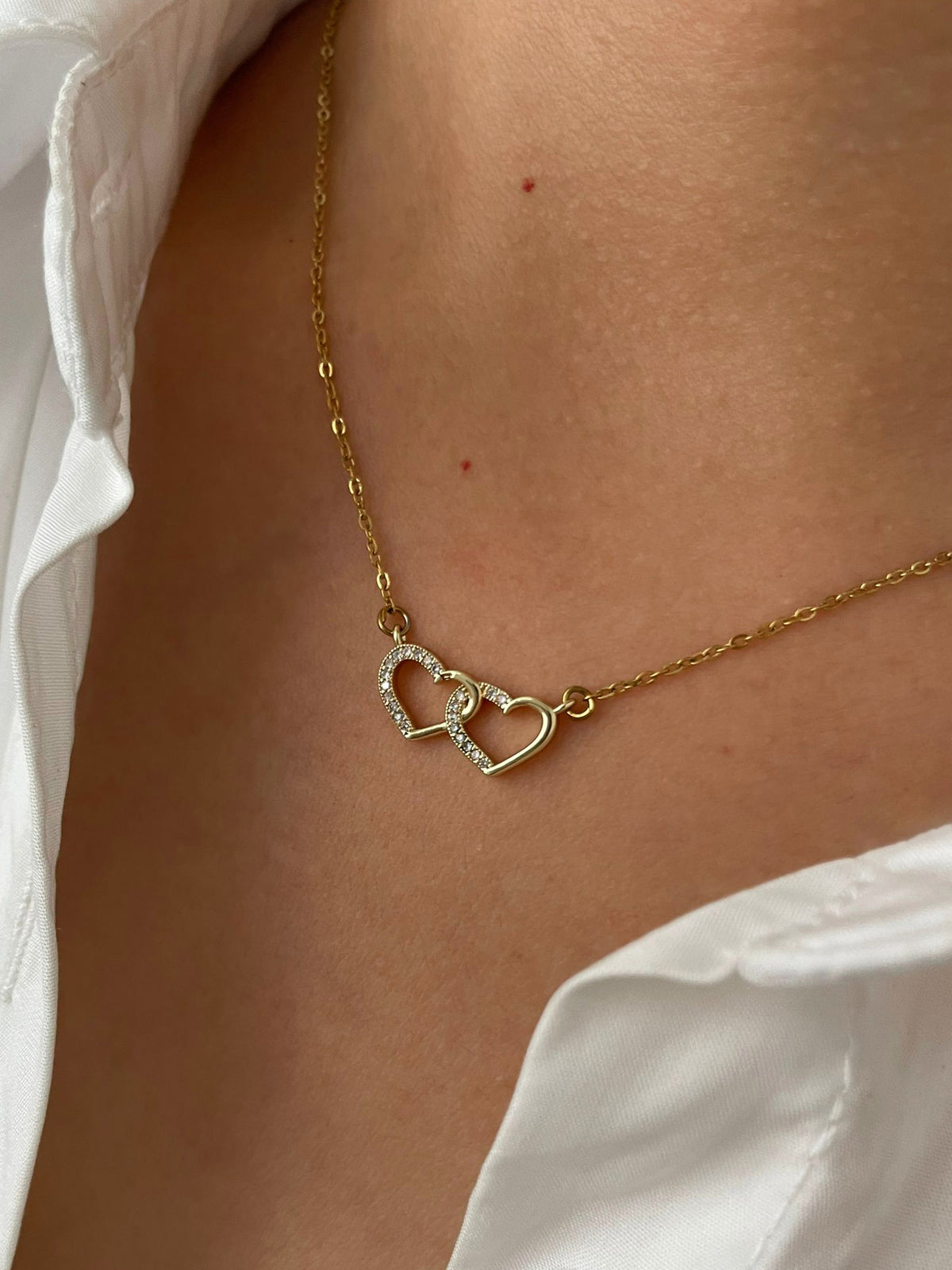 Gold necklace with a double heart-shaped pendant on a model