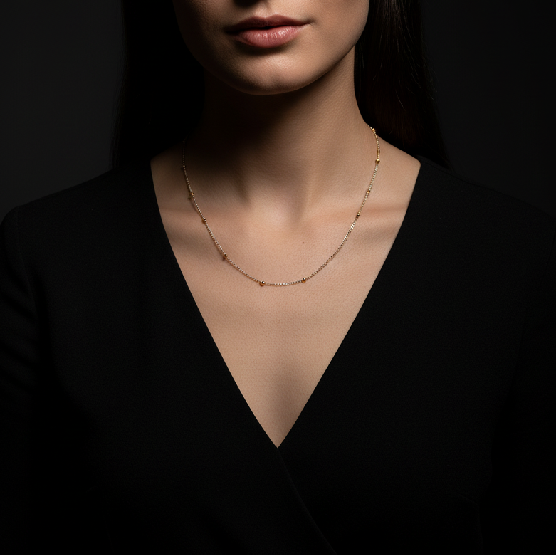 Woman wearing a delicate gold necklace against a dark background