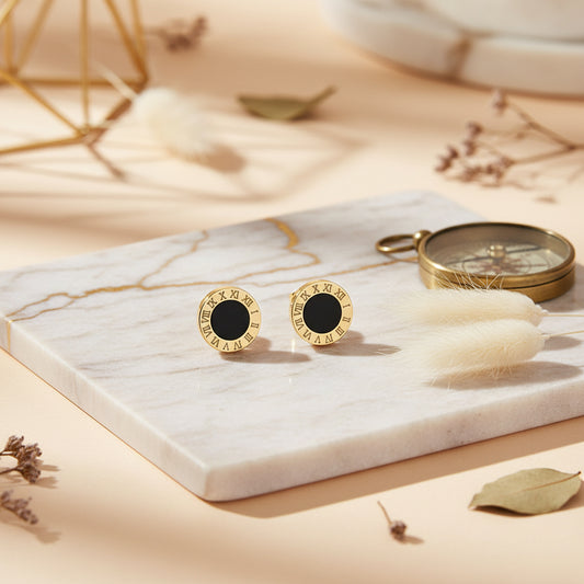 Modern gold circle studs with a black enamel centre and Roman numeral frame.