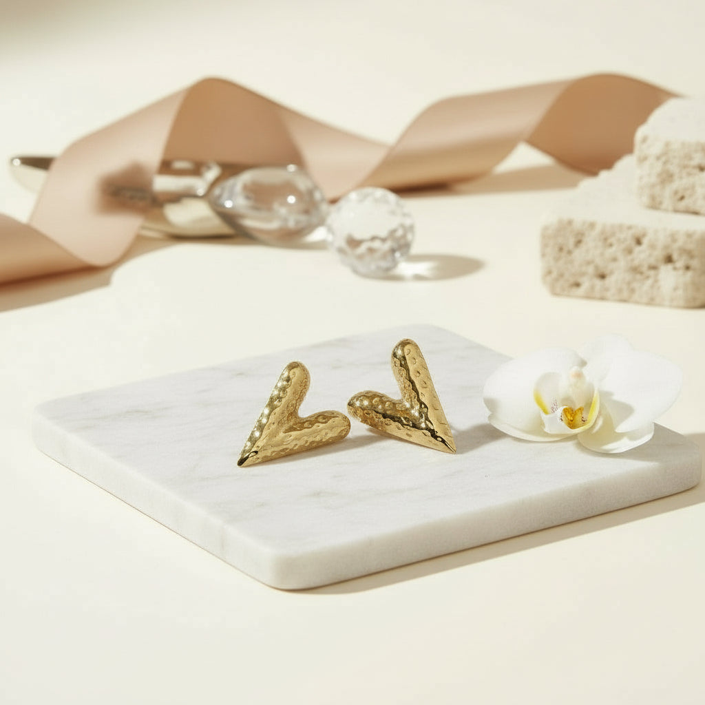 Elongated hammered gold heart studs with a sculpted romantic silhouette.