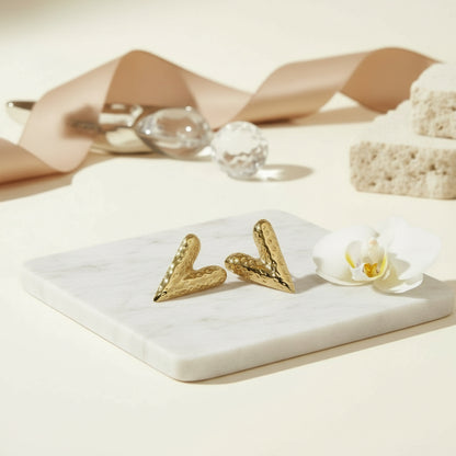 Elongated hammered gold heart studs with a sculpted romantic silhouette.